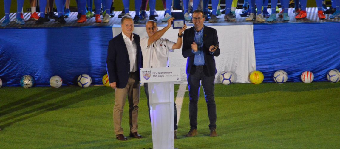 Foto: CFJ Mollerussa / Pau Del Valle alça la placa commemorativa pels seus 25 anys com a ‘speaker’ del club